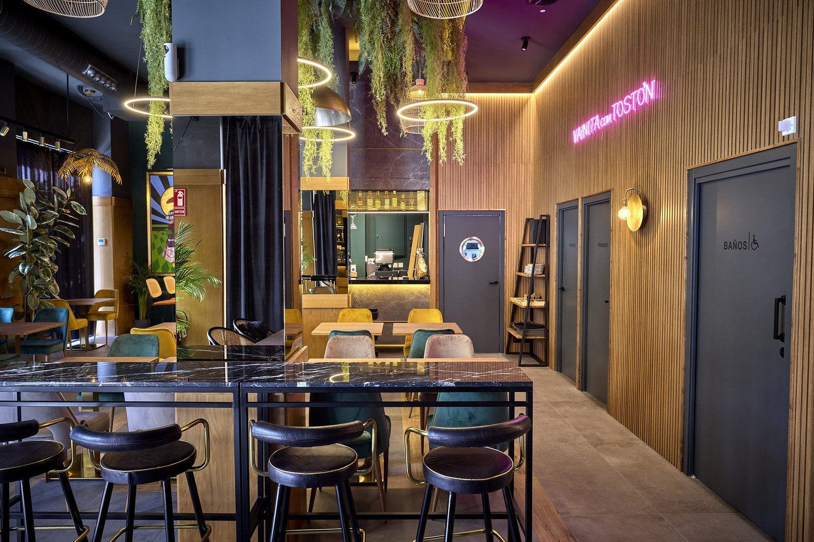 Sala de Vainita con Tostón: mármol negro, madera y el rótulo de neón rosa